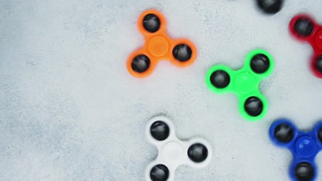 set of fidget spinners spinning on light gray table background with copy space, popular relaxing toy, generic design
