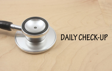stethoscope with word daily check up isolated on wooden background