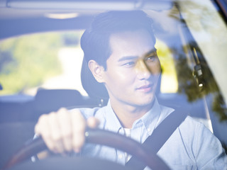 young asian man driving a car
