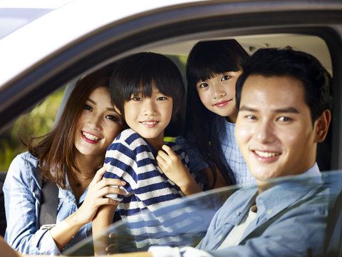 asian family enjoying a car ride, focus on the children. 