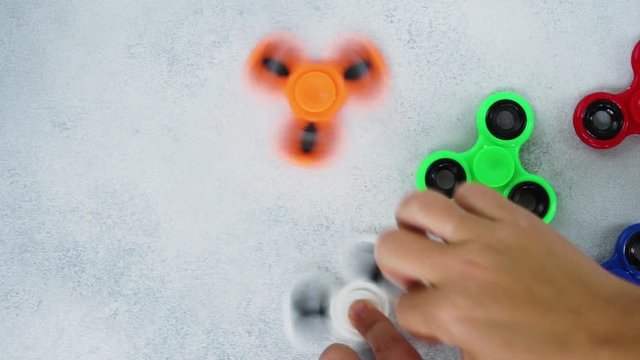 fidget spinners spinning on light gray table background with empty space, popular relaxing toy, generic design