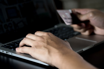 close up hands multitasking man using laptop and holding plastic credit card 