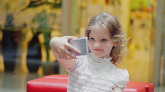 Close-up a nice girl of 7-9 years photographing herself using a smartphone, Selfie