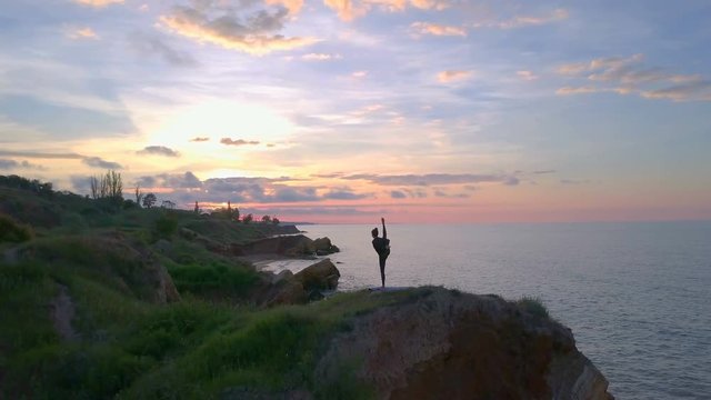 Flexible young girl doing yoga meditate sunrise coast namaste drone footage