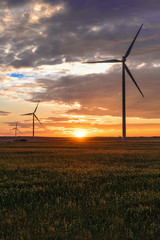 Puglia (Italy) - Wind farm with rock ruins, wind turbines and bales of hay at sunset