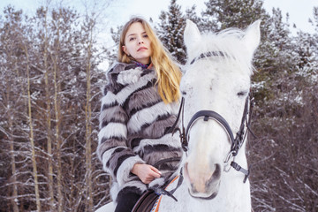 Fototapeta premium Nice girl and white horse in a forest in a winter