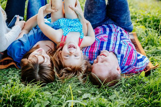 Family Parenting Love Togetherness Happiness Summer Concept. Happy parents with two daughter relaxing and having fun on the grass in summer time.