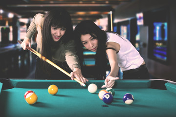 Pretty women playing billiards