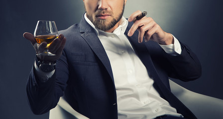 Cognac glass and cigar in hands of bearded man