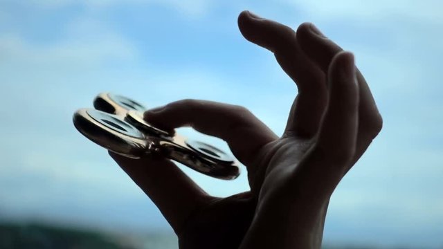 boy playing gold fidget spinner on blur top view background