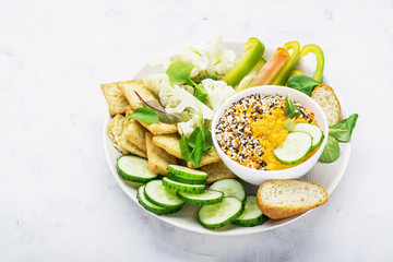 Vegetables bowl of sauce: carrot dip with slices of crispy bread, cucumber, sweet peppers, cauliflower, corn salad on a platter for a large company. Top view
