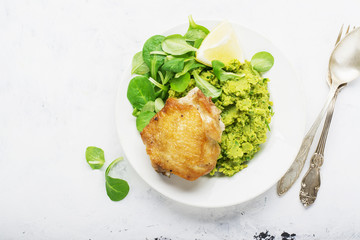 Easy healthy lunch: chicken thigh with mashed green peas and corn salad on a light background. Top view