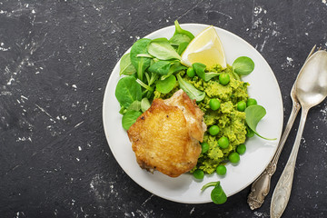 Easy healthy lunch: chicken thigh with mashed green peas and corn salad on a light background. Top view