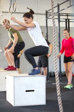 Determined Athletes Doing Box Jumping In Health Club