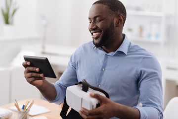 Positive cheerful man looking at the tablet screen