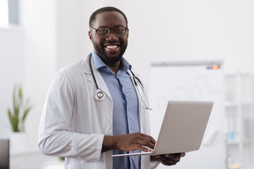 Positive professional doctor working on the laptop
