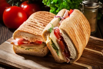 Foto op Plexiglas Snackbar Geroosterde panini met broodje ham, kaas en rucola