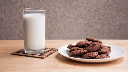 chocolate chip cookie and milk on wooden table