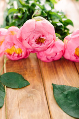 love, wedding, romance, nature, celebration concept - close-up of soft pink peonies with bright yellow core collected in gorgeous bouquet lying on wooden table