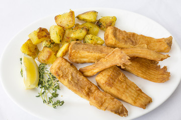 Fried fish garnished with potatoes, close up, top view at restaurant