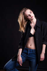 Gorgeous blonde in casual fashion clothes in studio photo on black background. Sexyality and sensuality