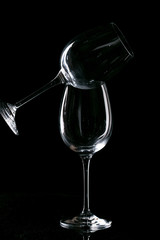 Two empty glasses for wine with an orange filter on a black background