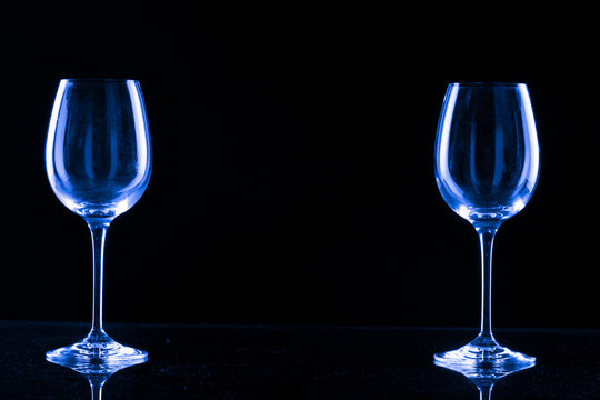 Two empty glasses for wine with an orange filter on a black background