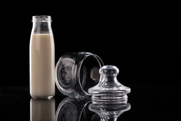 Milk in a bottle and empty bottle on a black background