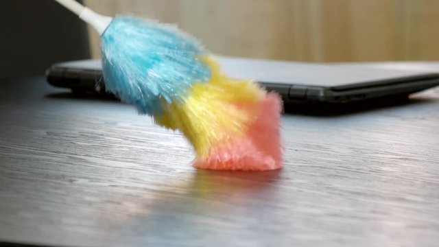 Colorful duster close up. Dust brush wiping wooden table. Office cleaning services.
