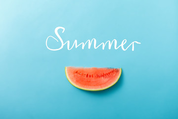 Slice of fresh ripe watermelon on blue painted wooden background with white handwriting