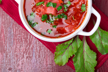 Ukrainian traditional borsch. Russian vegetarian red soup  in white bowl on red wooden background. Top view.  Borscht, borshch with beet.