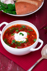 Ukrainian traditional borsch. Russian vegetarian red soup  in white bowl on red wooden background.  Borscht, borshch with beet.