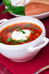 Ukrainian traditional borsch. Russian vegetarian red soup  in white bowl on red wooden background.  Borscht, borshch with beet.