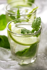 Healthy tasty fresh refreshing detox water in glasses with lime, mint and ice on wooden background. Closeup. Healthy Life Concept.