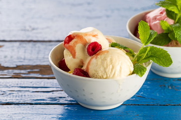 Tasty appetizing vanilla and strawberry ice cream with jam in bowls on wooden table. Closeup.