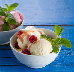 Tasty appetizing vanilla and strawberry ice cream with jam in bowls on wooden table. Closeup.