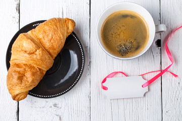 Croissant, coffee, postcard on table