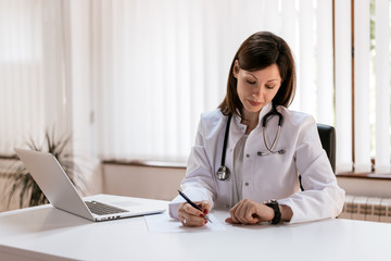 Doctor writing on a notepad in medical office