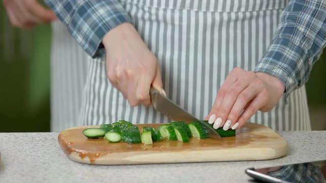 Hands of couple cooking. Pieces of cucumber on board. Love and health.