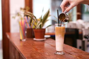 Pouring coffee in a coffee cup, preparing cappuccino.