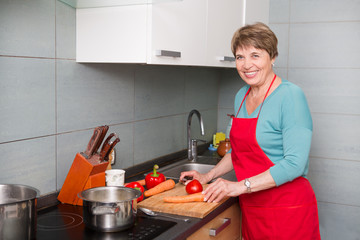 Happy elderly woman cooking  in kitchen at home