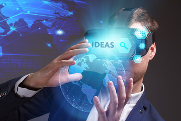 Business, Technology, Internet and network concept. Young businessman working on a virtual screen of the future and sees the inscription: Ideas