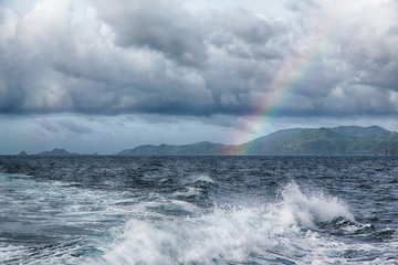 the rainbow from  ocean and island in background