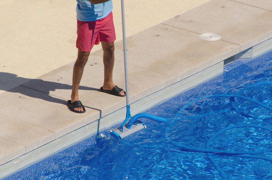 Man cleaning the swimming pool with a vacuum head