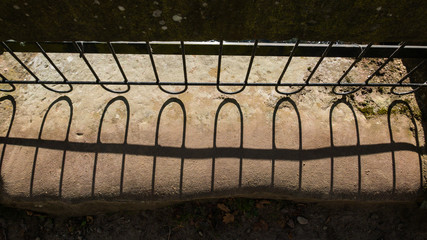 Shadows of metal railings on a sandstone bridge