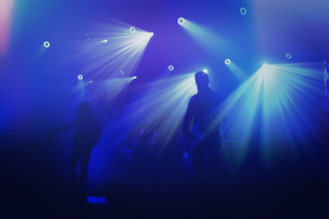 Rock band silhouettes on stage at concert.