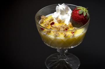 Vanilla pudding with strawberry and sour cream on black background