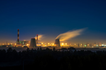 Fototapeta na wymiar Factories at night, the silhouettes of the pipe producing a noxious smoke into the sky..