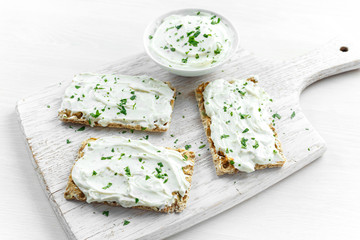 Homemade Crispbread toast with Cream Cheese and parsley on white wooden board background.