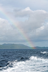 the rainbow from  ocean and island in background